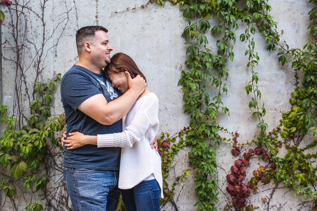 A couple cuddles outside of the Emily Carr building on Granville Island