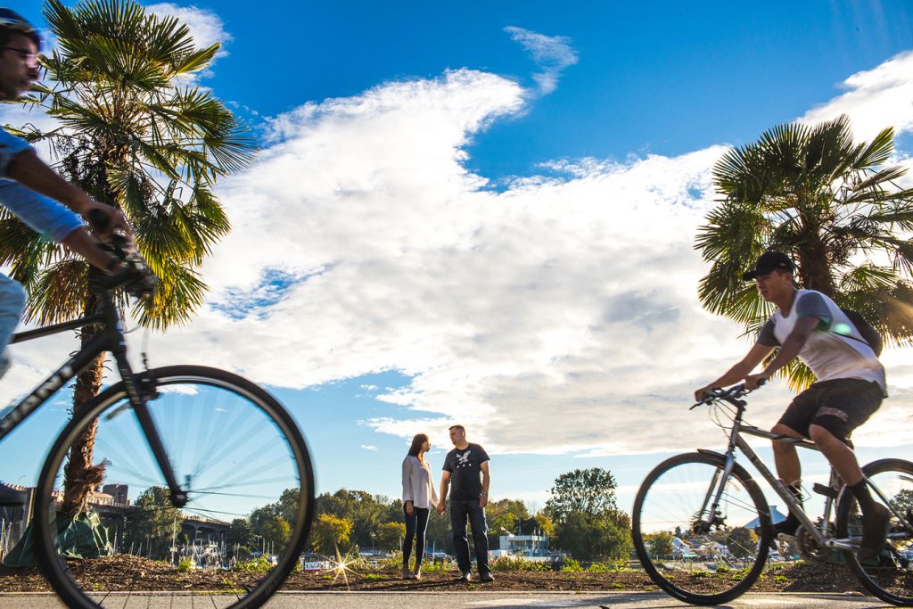 bicycles rush past a couple during their engagement session in Vancouver bc