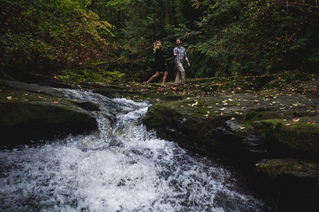 a couple holds hands and walks along the edge of kanaka falls in maple ridge