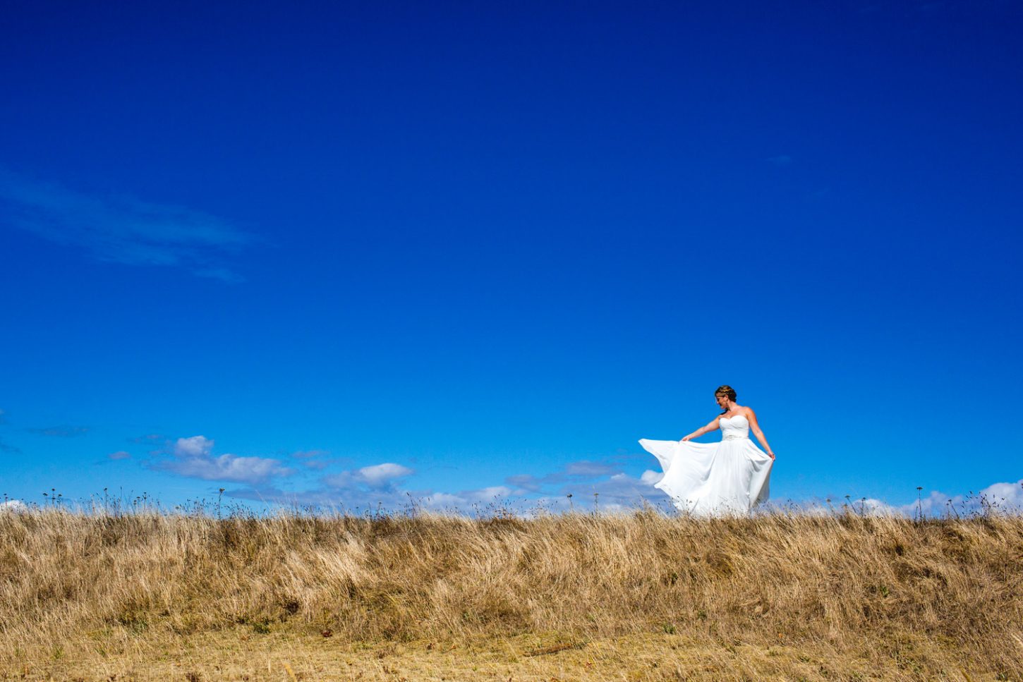 portrait of a bride's wedding dress blowing in the in wind at the beach