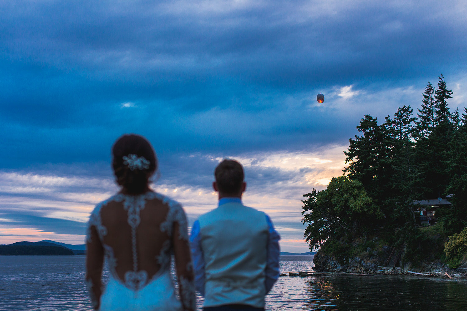 A bride and groom light a lantern near the sea at their Bodega Ridge Wedding