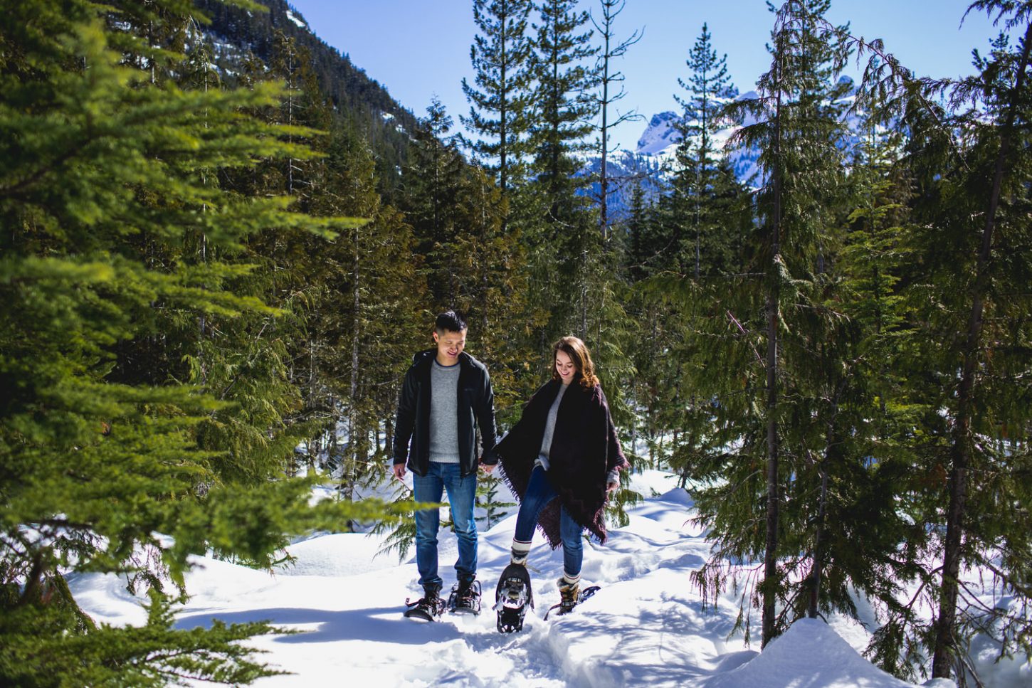 couple snowshoes along a trail at a sea to sky gondola engagement session